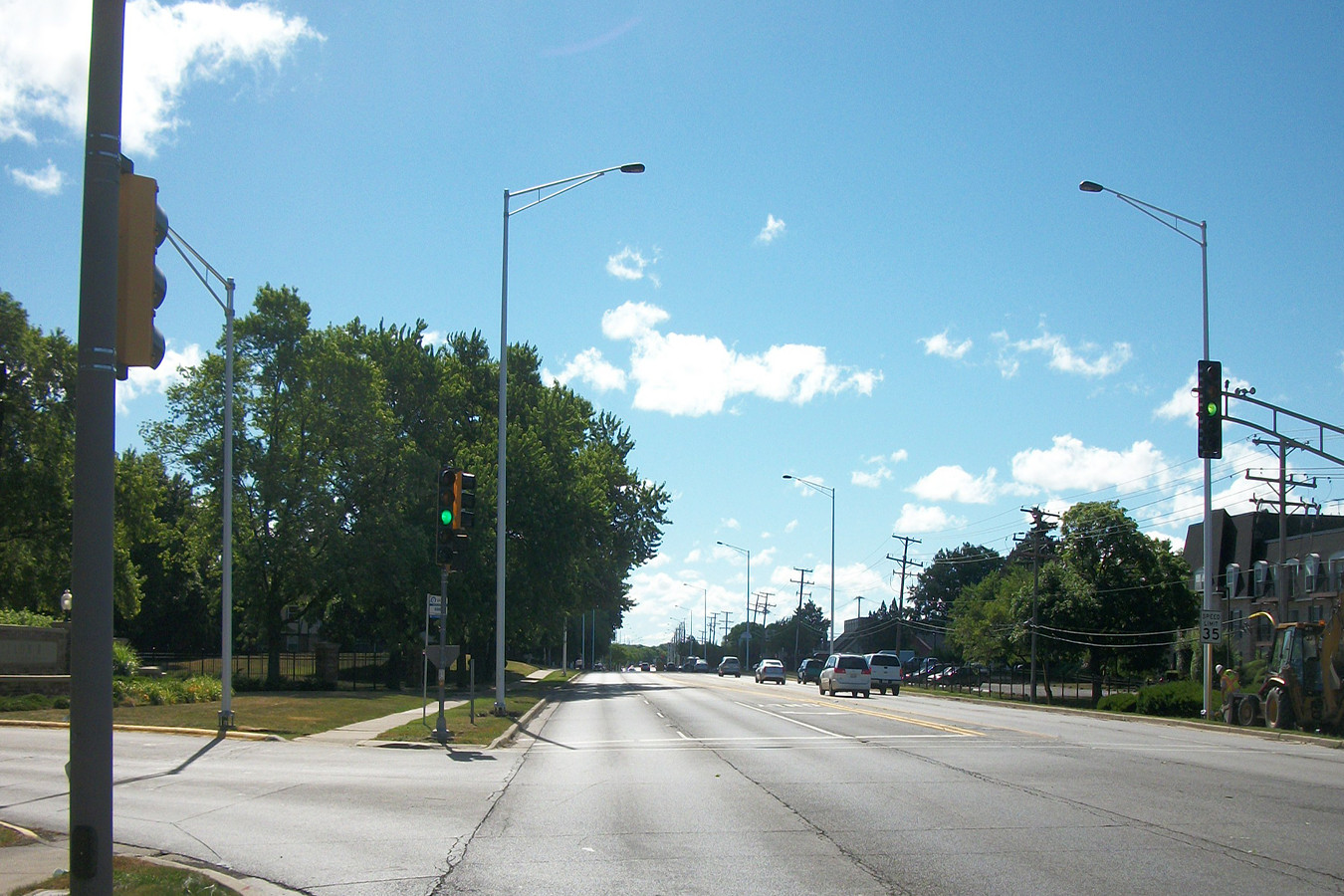 A street with cars driving down it and trees in the background.