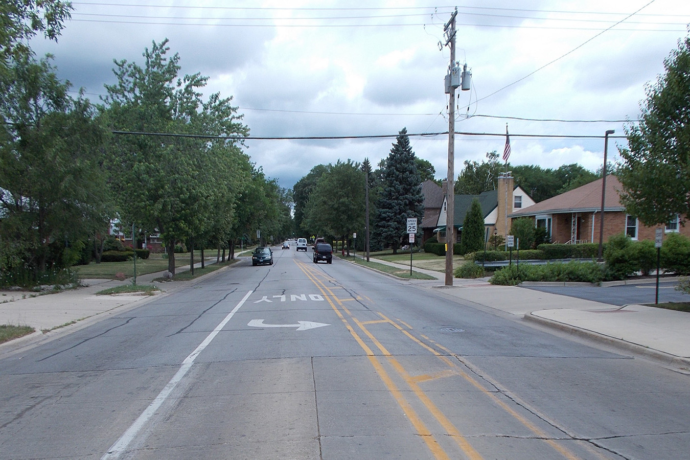 A street with cars driving down it and trees in the background.