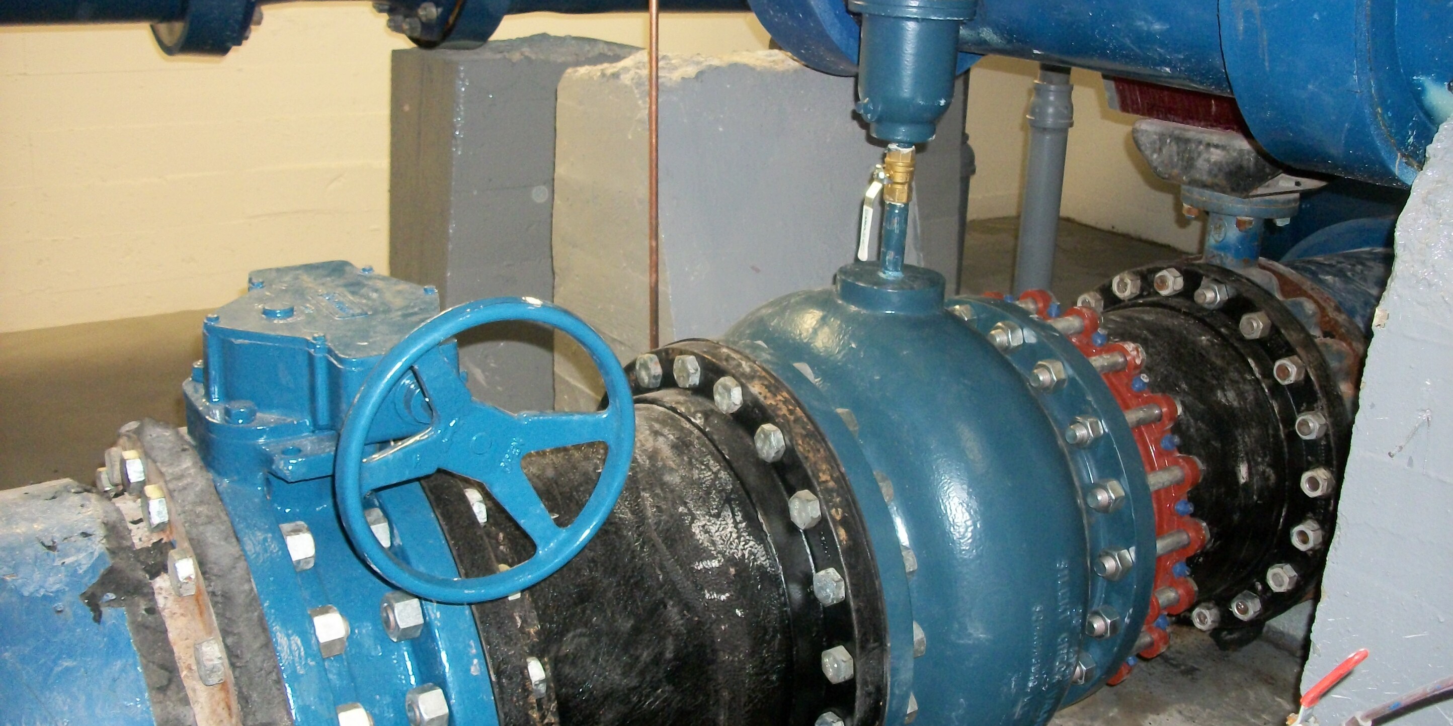 A blue and black pipe sitting next to pipes.
