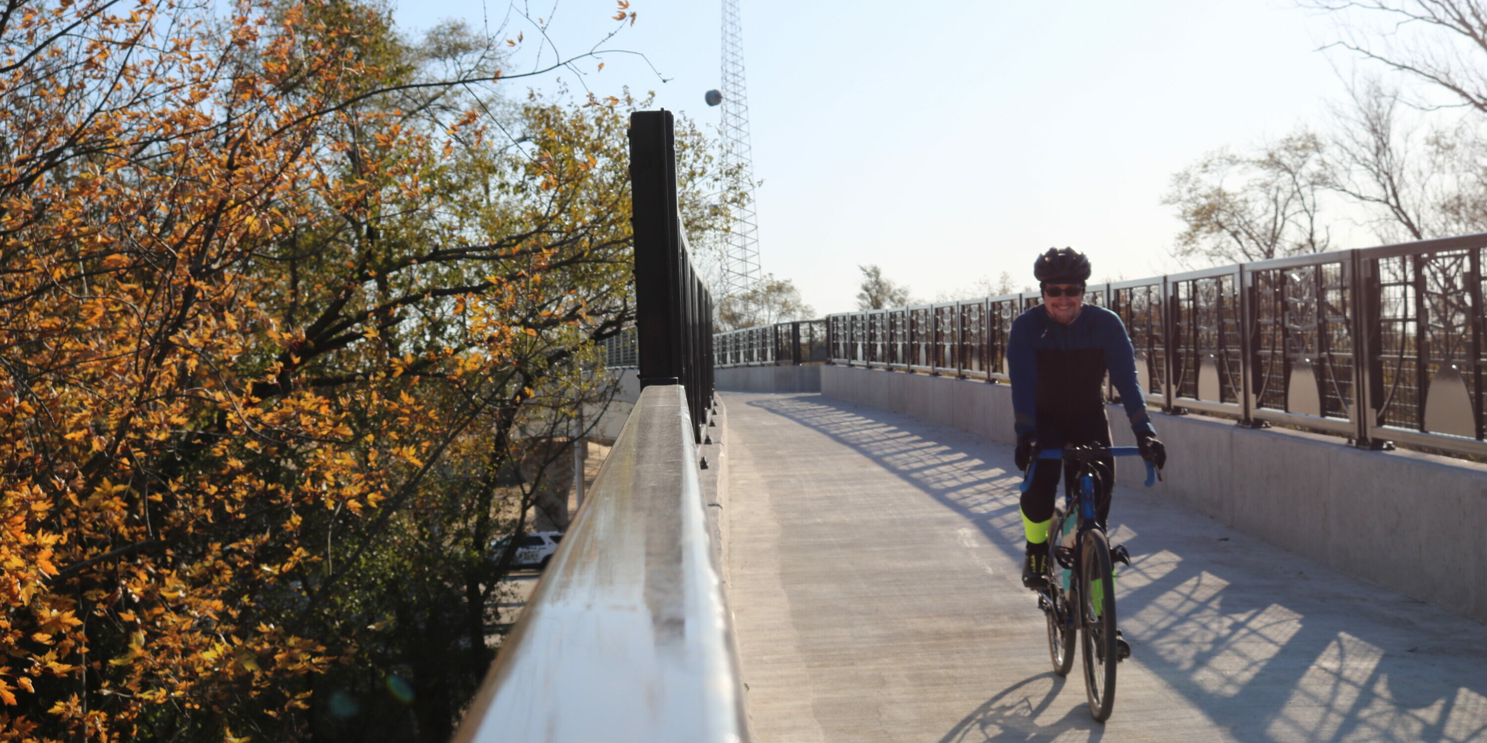 A man riding his bike on the side of a bridge.