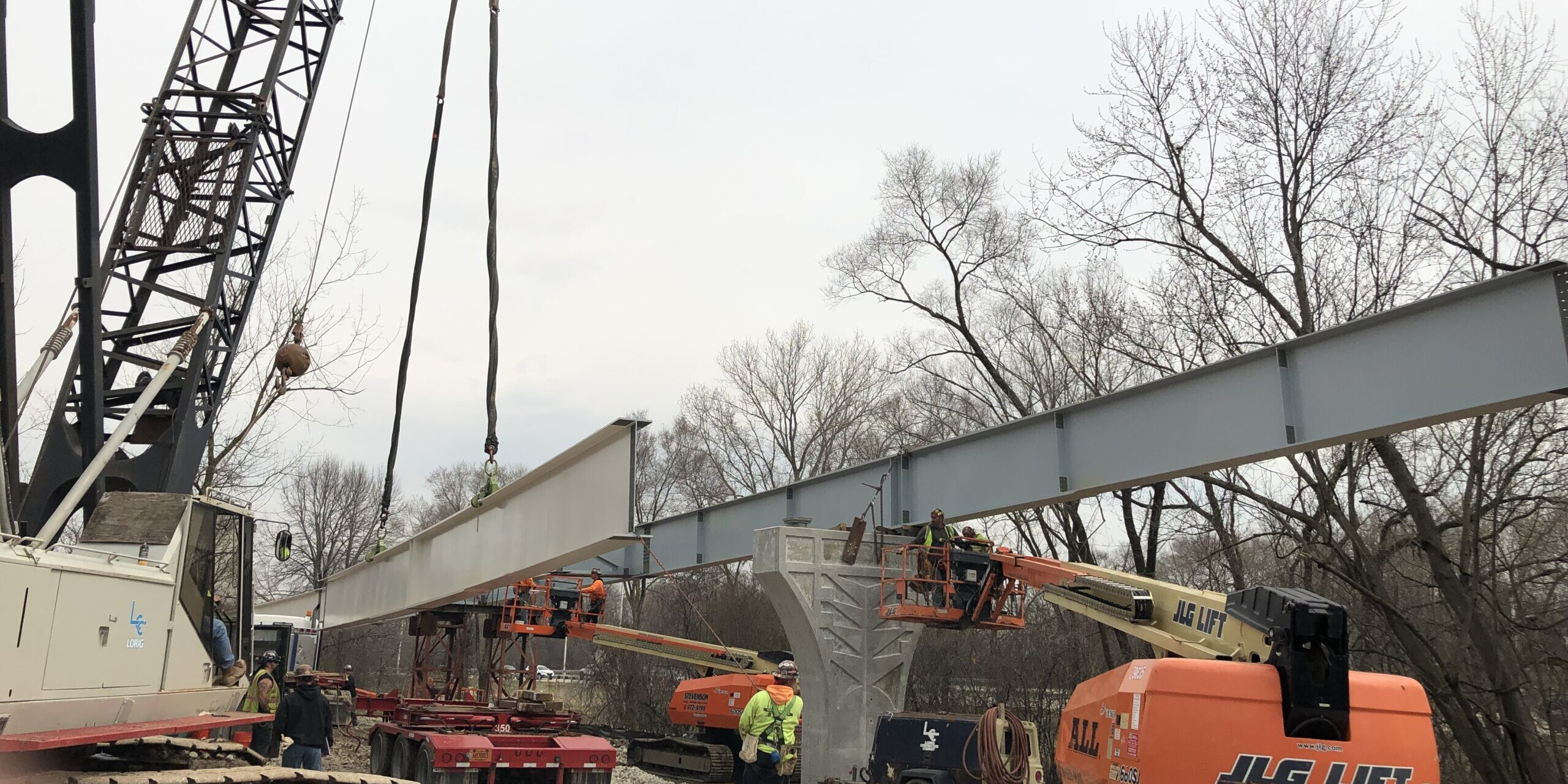 A crane is lifting a bridge over the river.
