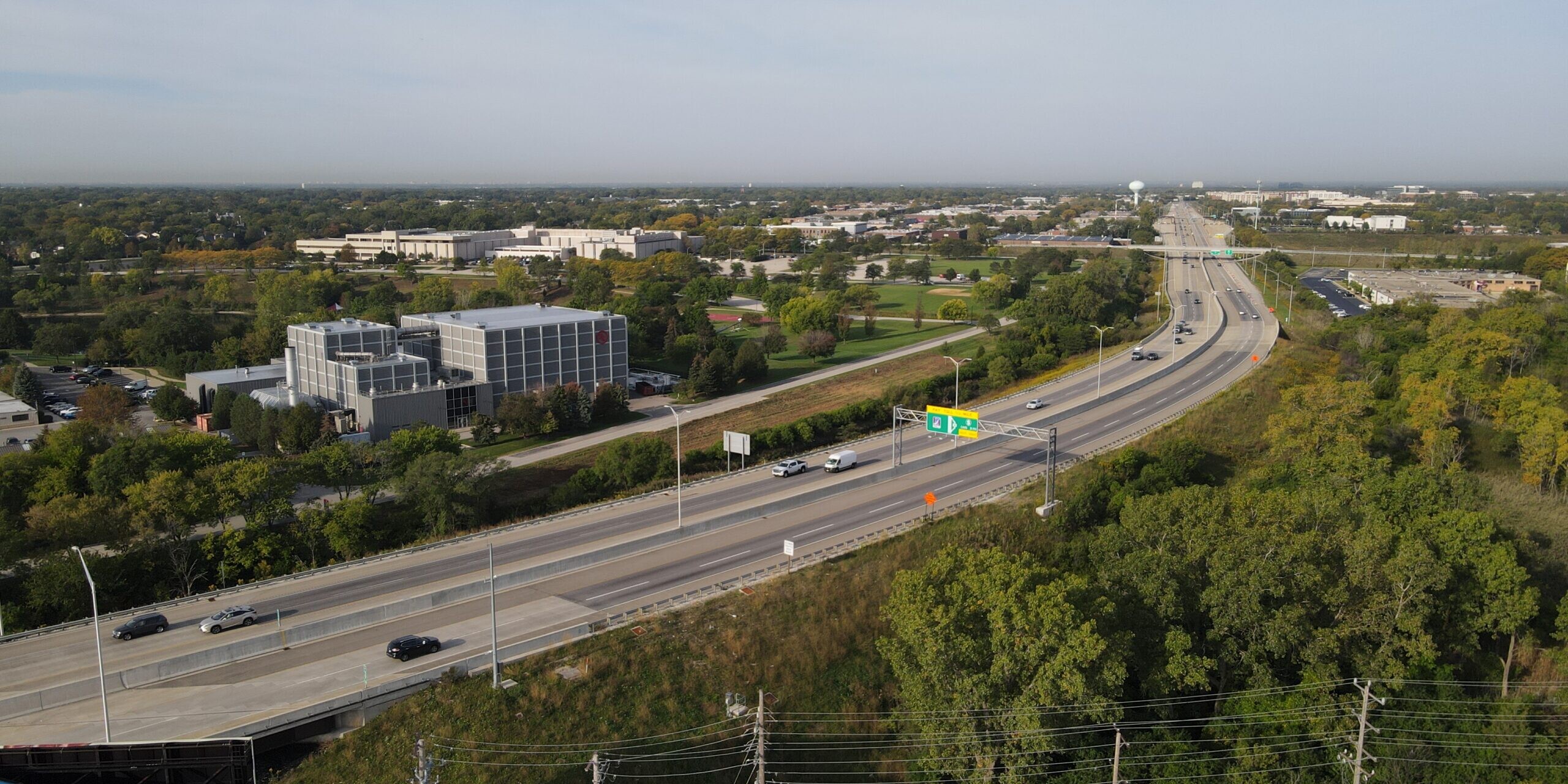 A highway with cars driving on it and trees in the background.