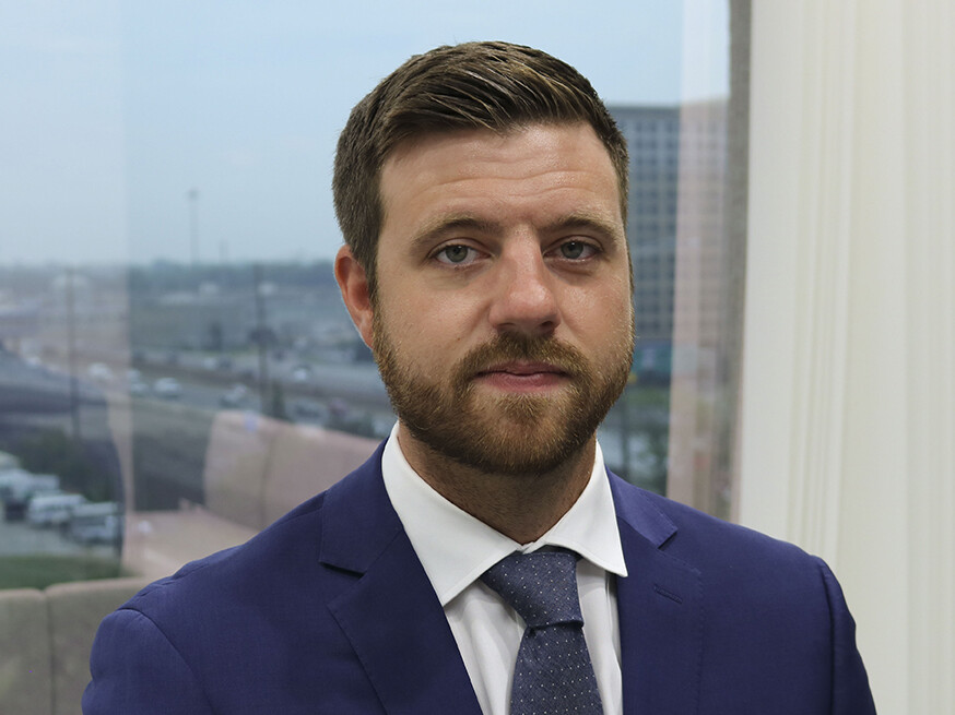 A man in a suit and tie standing next to a window.