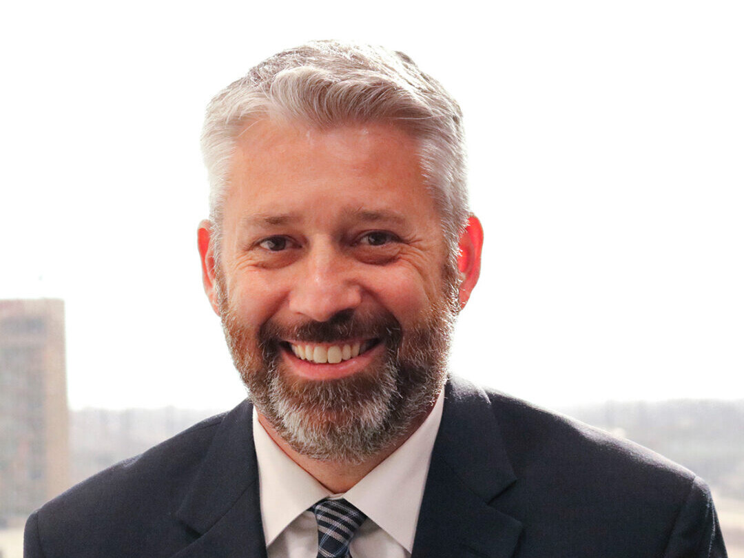 A man in suit and tie smiling for the camera.