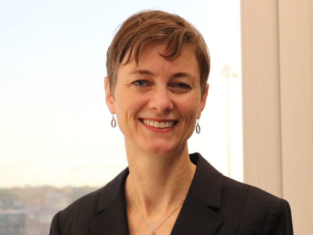 A woman in a black jacket smiling for the camera.