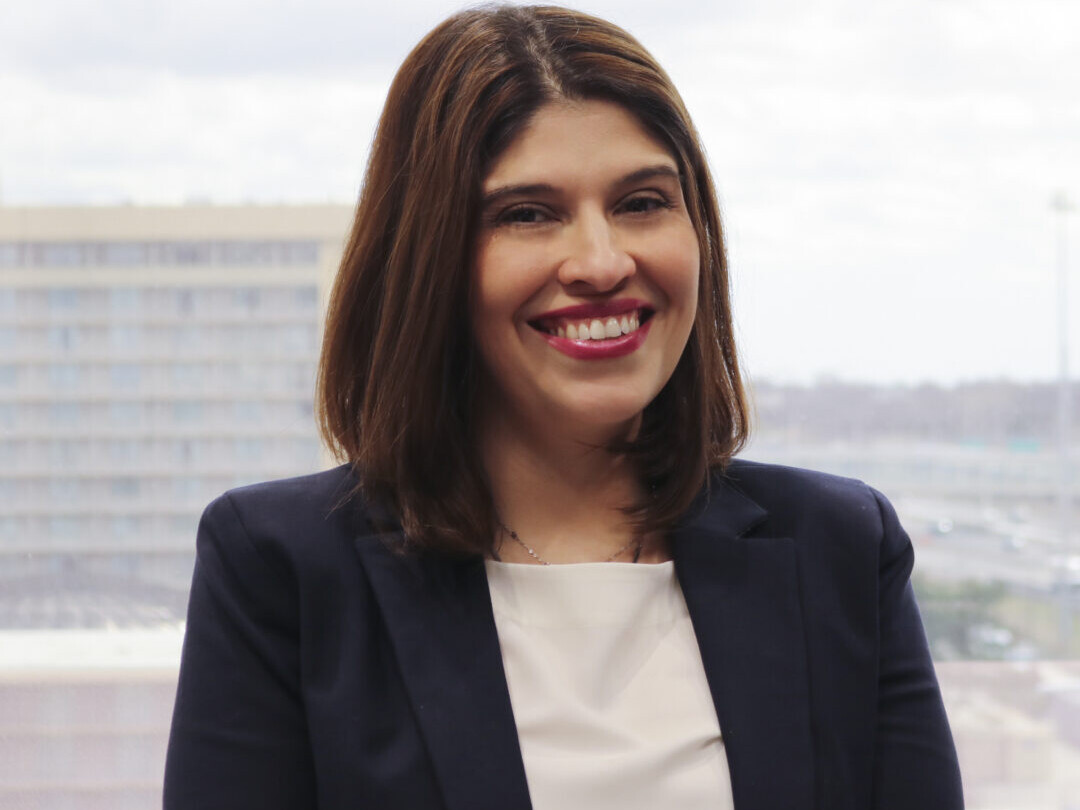 A woman in a suit smiling for the camera.