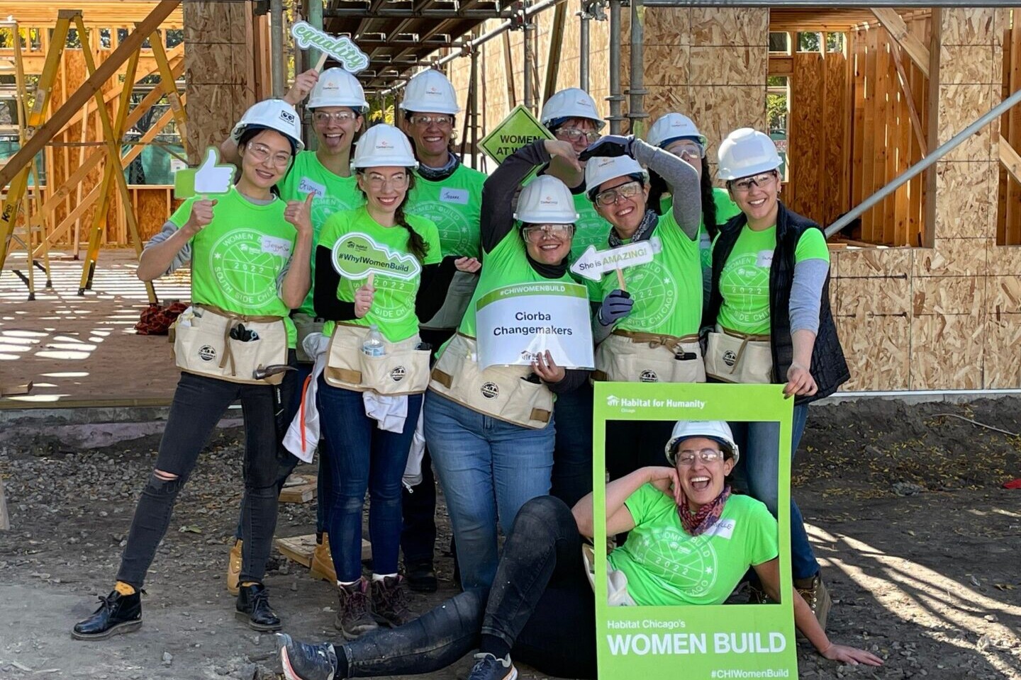 A group of people wearing hard hats and holding signs.