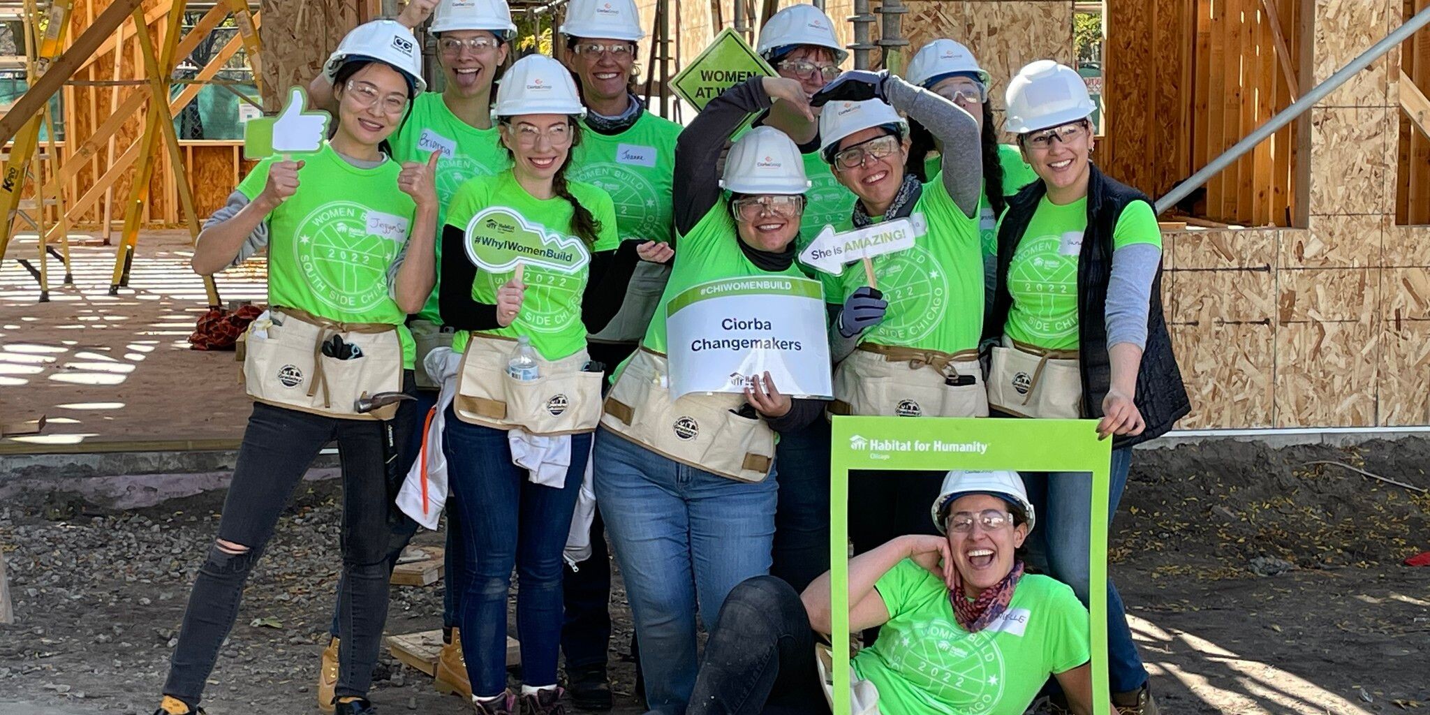 A group of people wearing hard hats and holding signs.