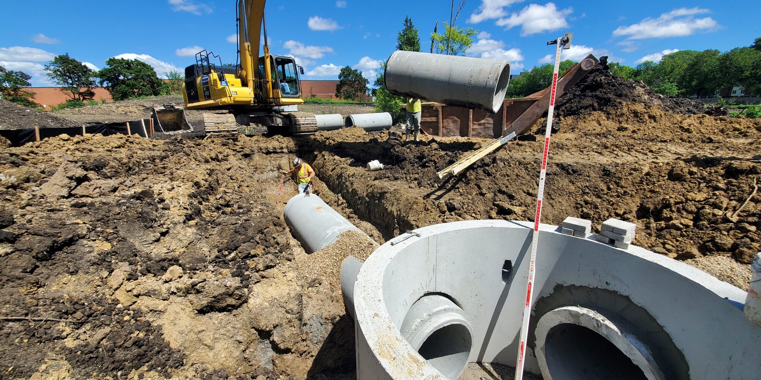 A construction site with a large pipe and a yellow tractor.