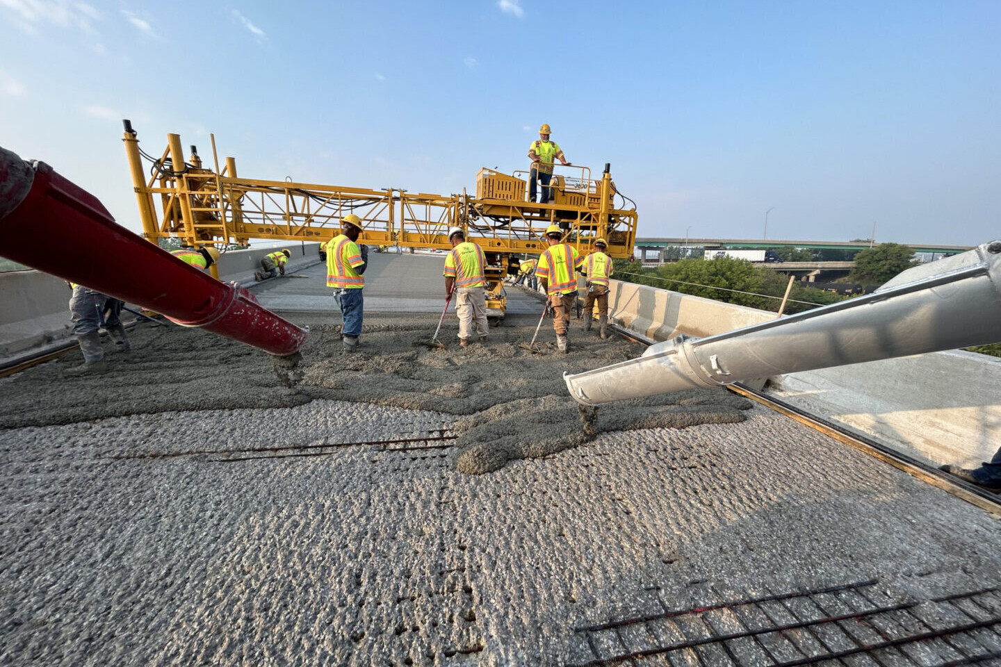 A group of construction workers standing on top of a concrete slab.