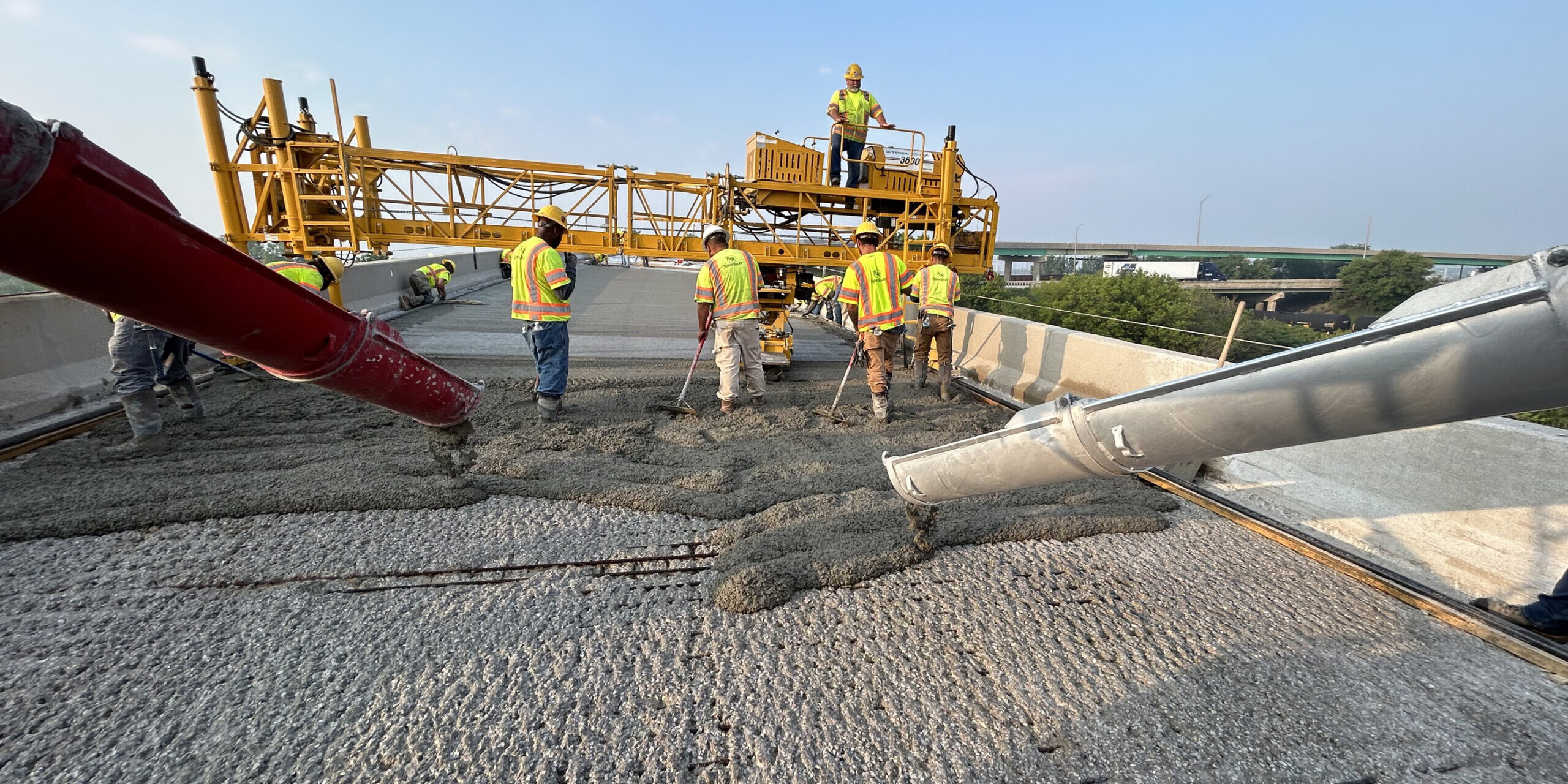 A group of construction workers standing on top of a concrete slab.