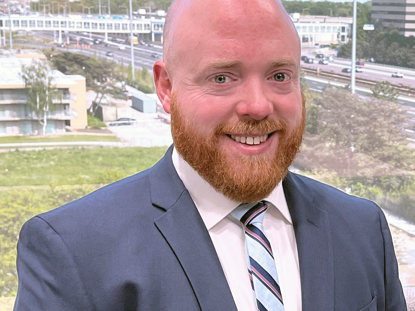 A man in suit and tie standing next to a wall.